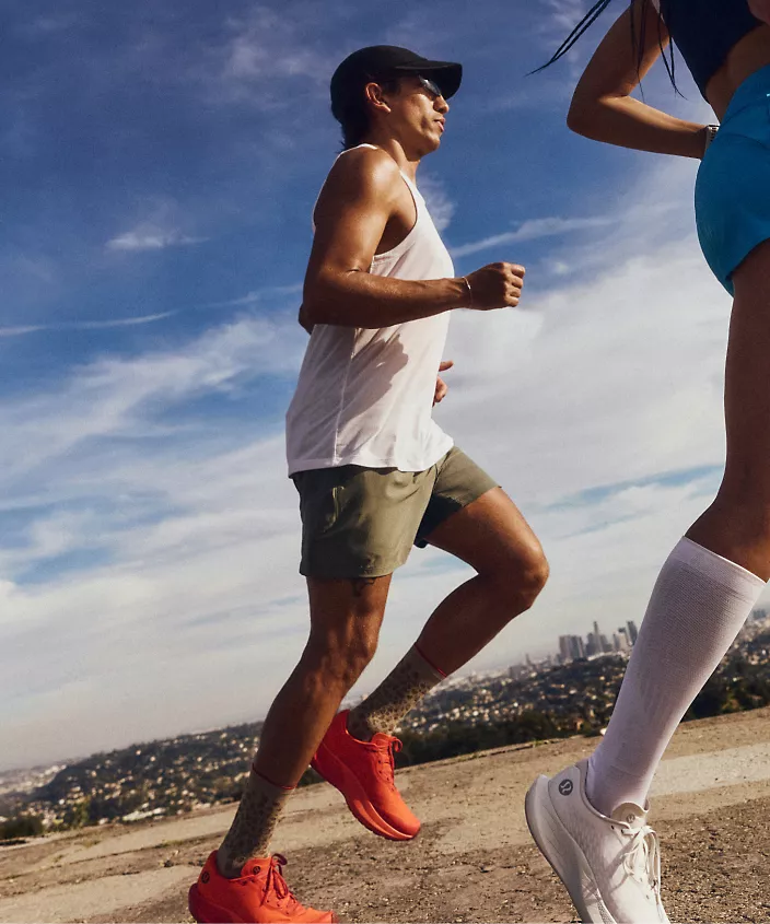 A person jogs outside in front of shuttered storefronts, wearing lululemon spring run gear. 